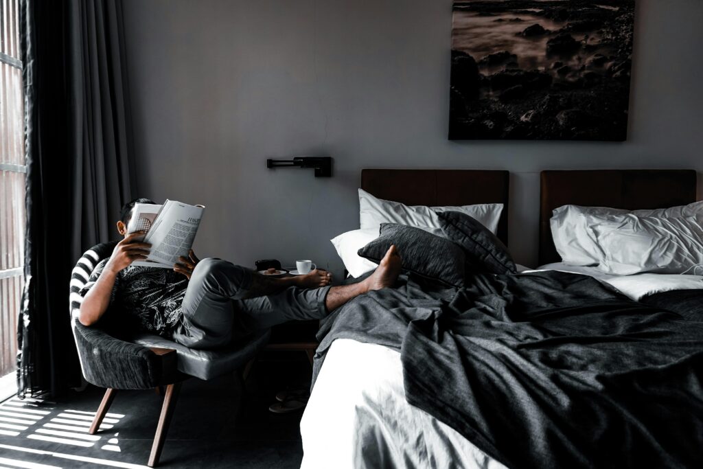 Person reading comfortably in a cozy, monochrome-themed bedroom, perfect for lounging and relaxation.